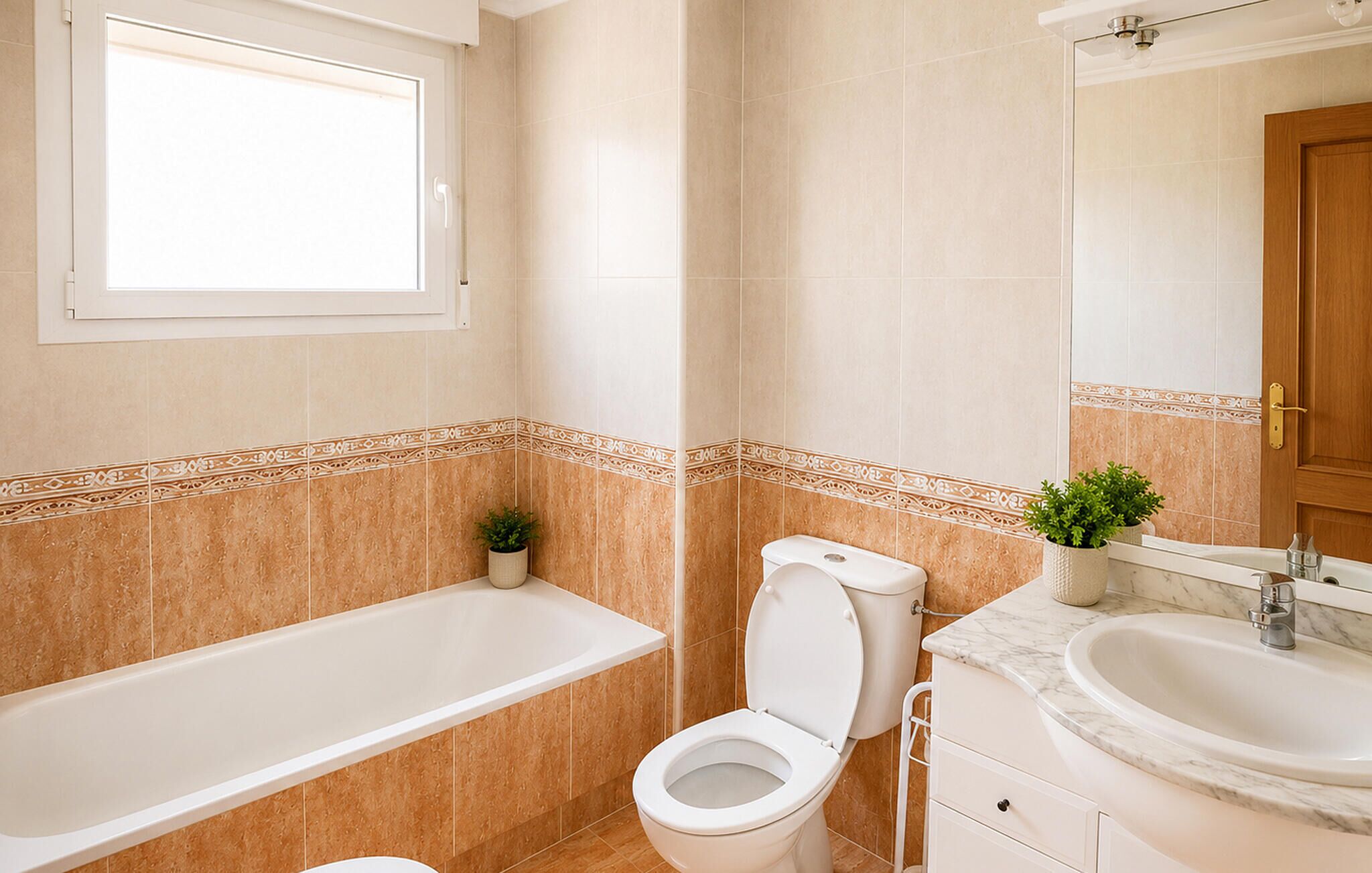 A bathroom with a bathtub, toilet, sink, and a window.