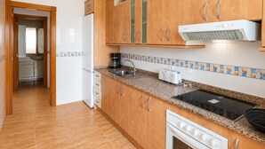 Una cocina con armarios de madera, horno empotrado, microondas y fregadero.