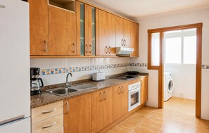 Eine Küche mit Holzausstattung, Backofen, Kaffeemaschine und Waschmaschine.