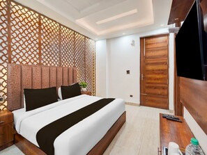 Ein modernes Hotelzimmer mit Bett, Holz-Kopfteil, Fernseher, Holztür und einer dekorativen Wandverkleidung.