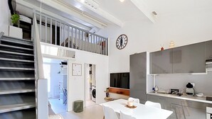 A modern kitchen with a dining area, built-in appliances, and a staircase leading to a loft. - Village house within walking distance of shops and sea (le barcares)