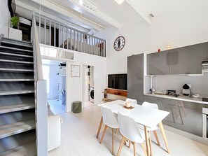 Eine moderne Küche mit Essbereich, integrierten Geräten und einer Treppe, die zu einer Mansarde führt.
