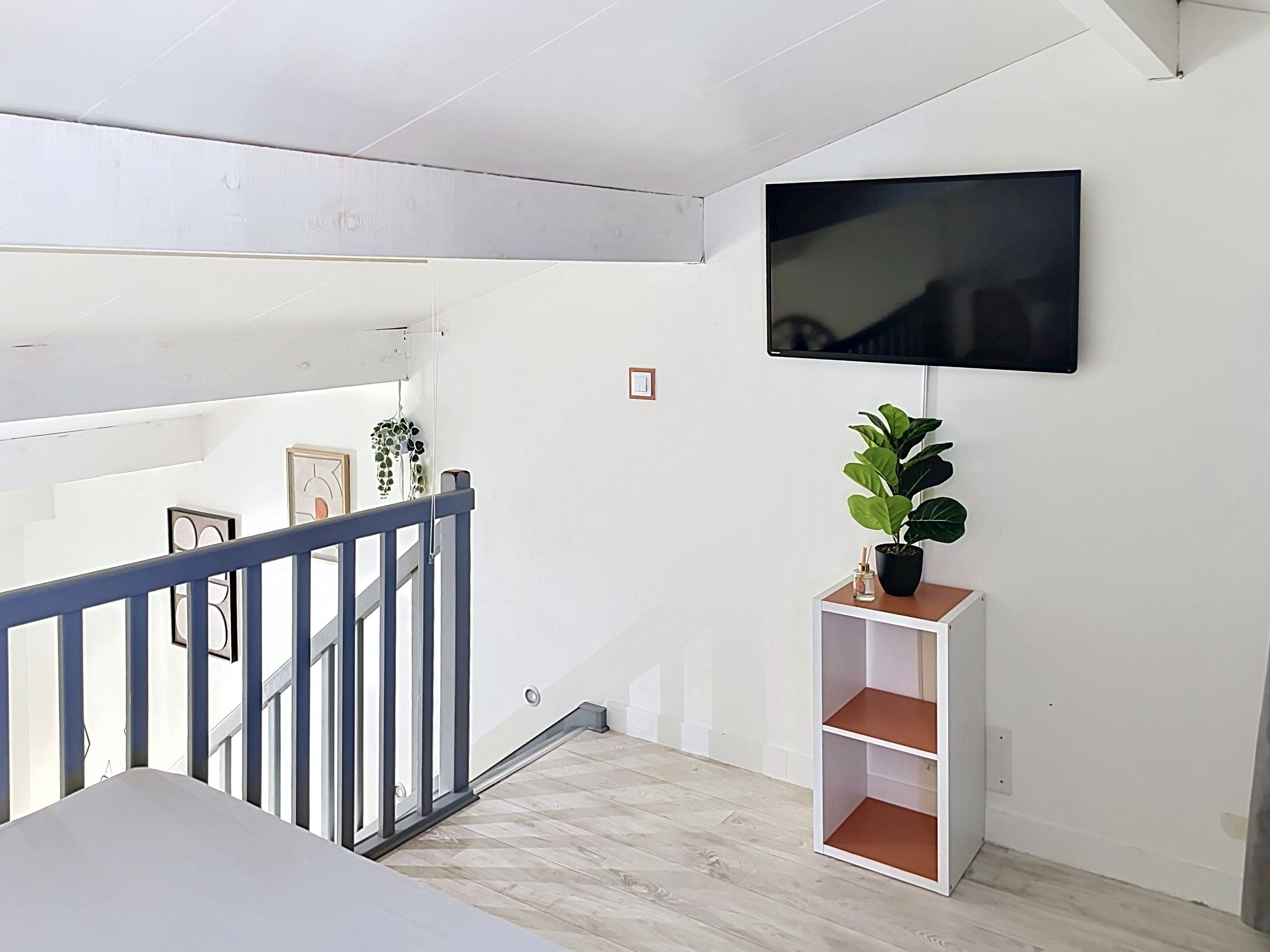 Ein modernes Interieur mit Treppe, Wand-Fernseher und Zimmerpflanze.