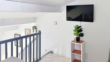 Ein modernes Interieur mit Treppe, Wand-Fernseher und Zimmerpflanze.