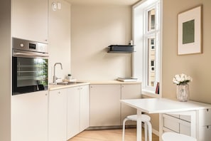 Une cuisine moderne avec des meubles blancs, un four encastrĂ©, un Ă©vier et une fenĂȘtre.