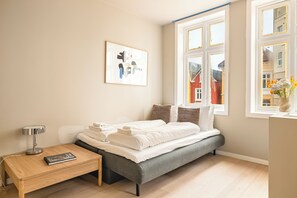 A modern bedroom with a bed, bedside table, lamp, and artwork.