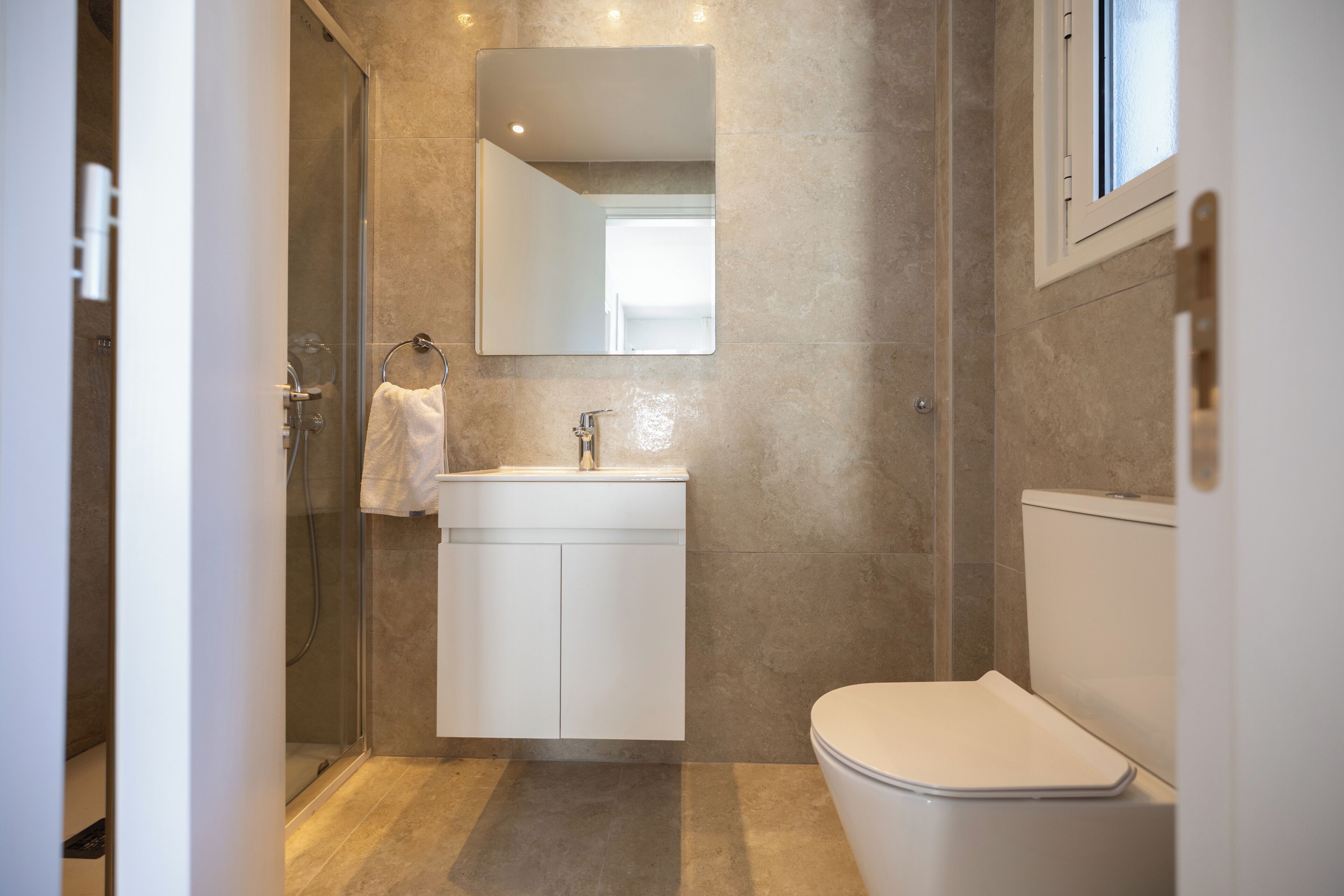 A modern bathroom with a glass shower enclosure, a white sink, and a toilet.