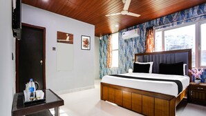 Hotelkamer met een houten plafond, een bed met donker hoofdeinde, een bureau met stoel en een raam met gordijnen.