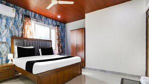 Een slaapkamer met een bed, nachtkastje, bureau, kledingkast en een plafondventilator.