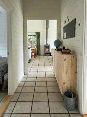 A hallway with a tiled floor, a wooden cabinet, a globe, and a fireplace. - Summer house with path to pier by fjord (Skibby)