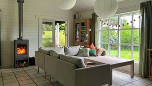Una sala de estar con chimenea, sofá, mesa y vistas al exterior.