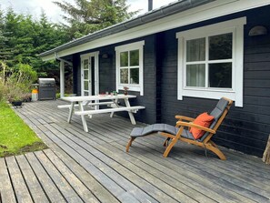 Eine Holzterrasse mit Picknicktisch und Liegestuhl.
