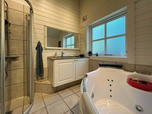 Ein Badezimmer mit Dusche, Waschbecken mit Spiegel, Fenster und Badewanne.