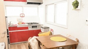 A compact kitchen with red cabinets, a stove, and a dining area with a wooden table and chairs. - 3 minutes from Roppongi-itchome station! A house, 2 stories, private! Conveniently located near convenience stores [8 minutes from Roppongi Station on the Hibiya Line]. (Minatoku)