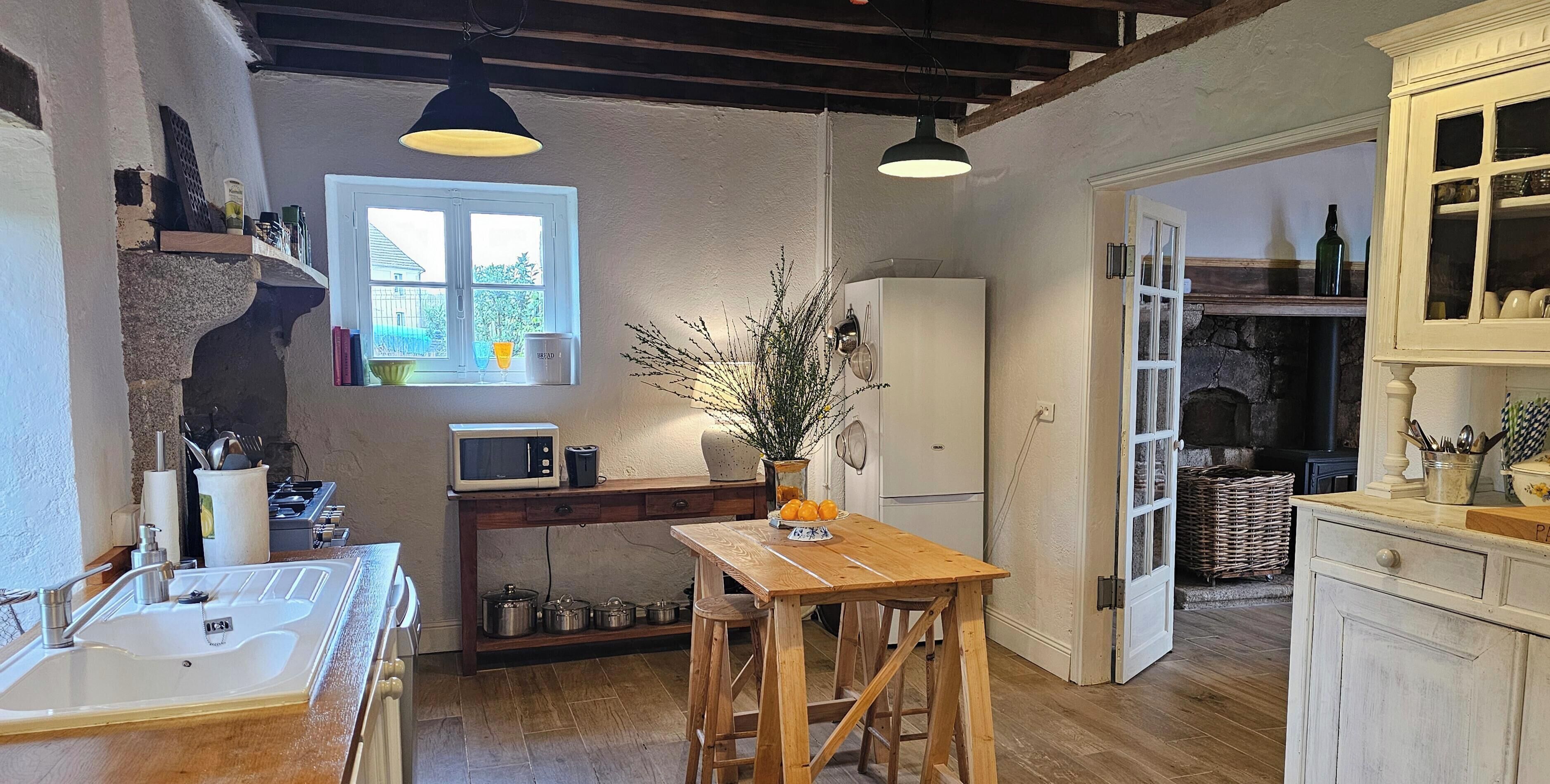 A kitchen with a wooden table, a sink, a microwave, and a refrigerator.