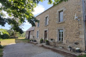 A stone building with multiple windows and a gravel driveway. - Charming house nestled in peaceful, authentic surroundings. (Ars)