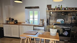 Una cocina con armarios blancos, encimera de madera, una ventana, una estufa y un lavabo.