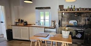 A kitchen with white cabinets, a wooden countertop, a window, a stove, and a sink. - Charming house nestled in peaceful, authentic surroundings. (Ars)