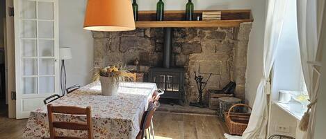 A rustic dining area with a stone fireplace, wooden beams, and a table set for four.