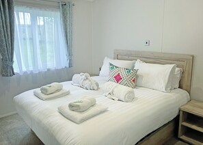 A neatly made bed with rolled towels, a patterned pillow, and a bedside table. - Clearwater Pet Friendly (No Hot Tub) (Hexham)