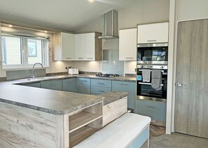 A modern kitchen with a built-in island, stainless steel appliances, and light blue cabinetry. - Clearwater Pet Friendly (No Hot Tub) (Hexham)