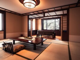 Una habitación japonesa tradicional con suelo de tatami, una mesa baja con posavasos, un cojín, un banco y una puerta corrediza que da a otra habitación.