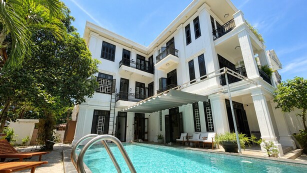 A multi-story hotel with a swimming pool, outdoor seating, and a covered patio area. - Peaceful Studio near Hoi An Old Town - Pool & Working Space (Đà Nẵng)