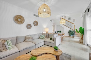 Ein modernes Wohnzimmer mit einer Couch, einem Couchtisch und einer Pendelleuchte.