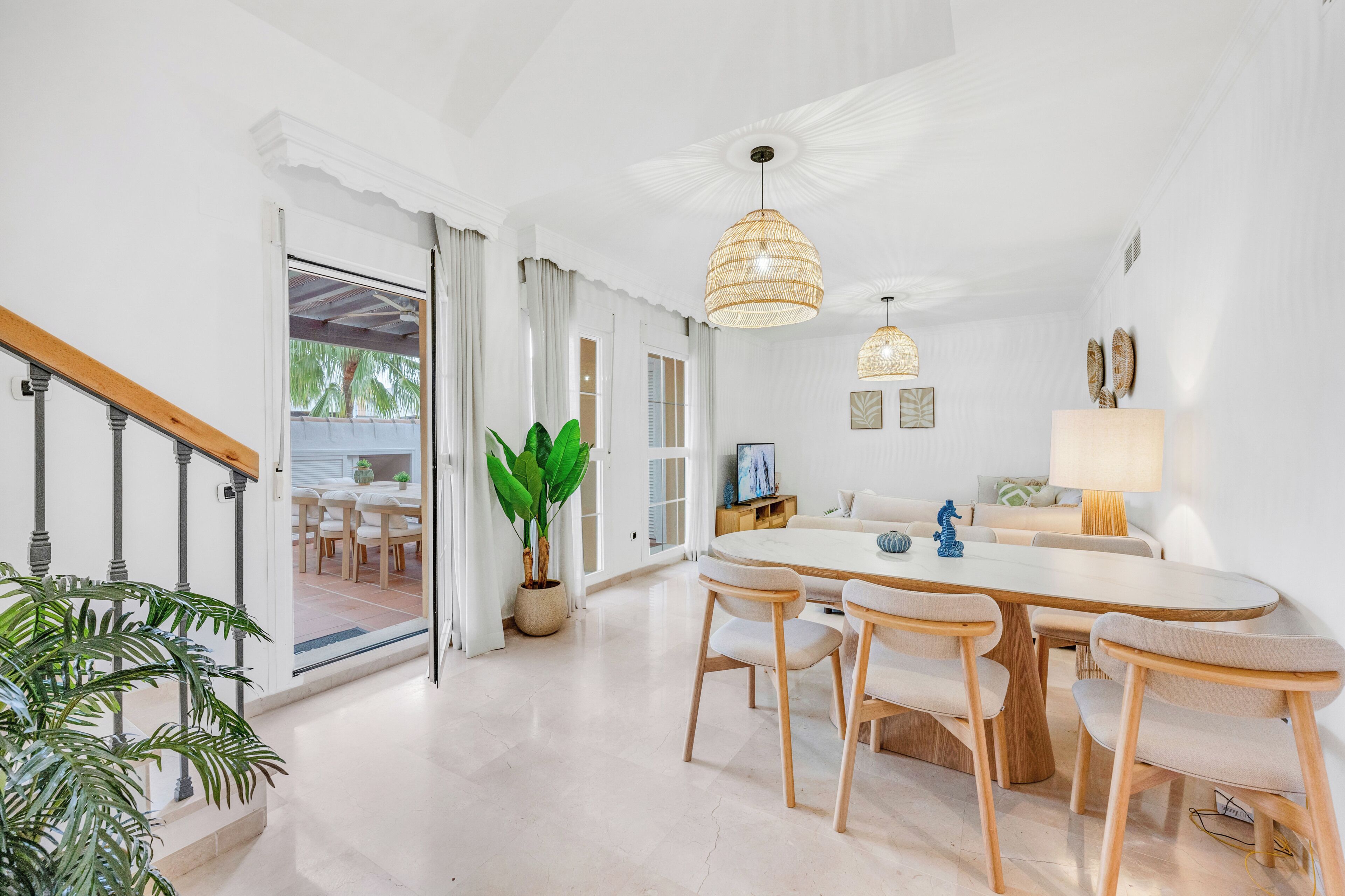 A modern dining area with a round table, wooden chairs, and pendant lighting.