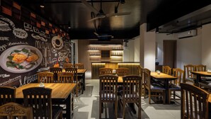 Un ristorante con tavoli e sedie in legno, una parete con il menu scritto su una lavagna e un arredamento moderno.