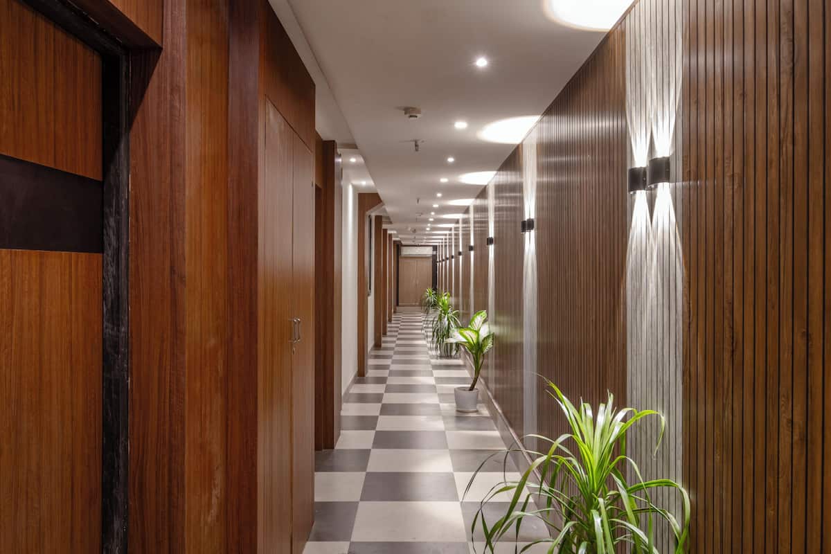A hallway with wooden paneling, a checkered floor, and potted plants.