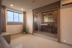 A modern bathroom with a glass shower enclosure, a large mirror, and a sink.
