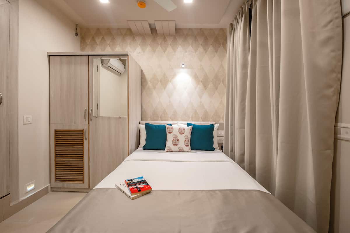 A bedroom with a bed, a wardrobe, a mirror, and a book on the bed.