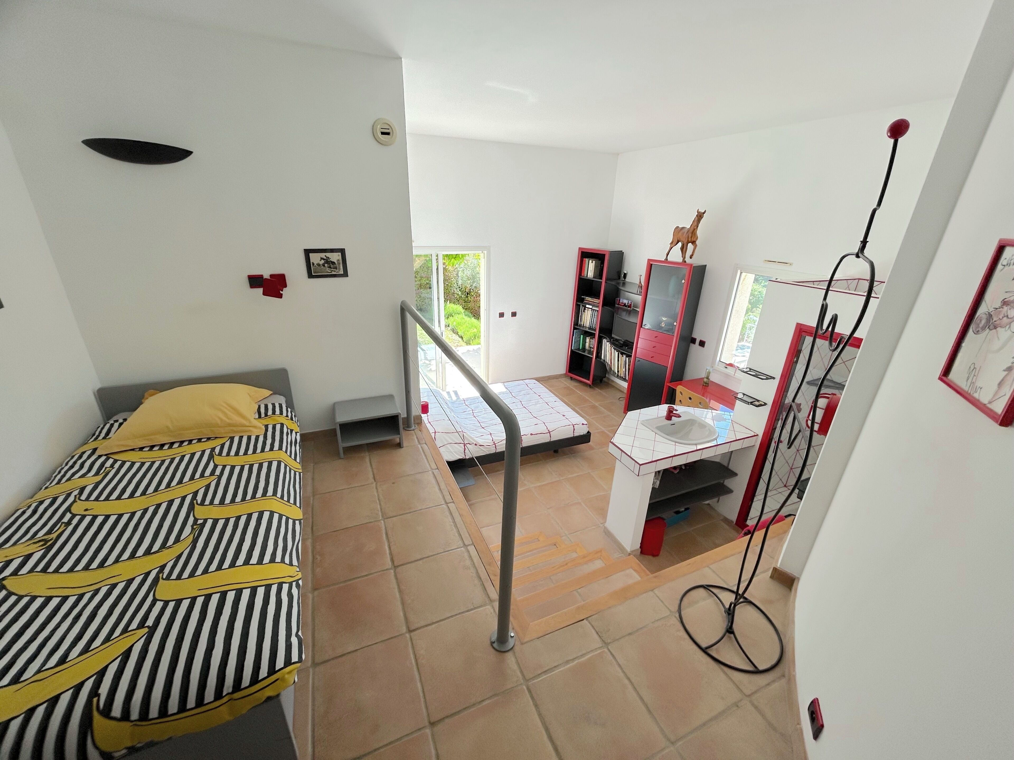 Ein Schlafzimmer mit einem Bett, einem kleinen Schreibtisch, einem Spiegel und einem Kleiderschrank.