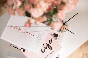 A table with documents, a glass of water, and a vase of pink flowers. - Spacious 115m² Lancaster| Pool,Lake View,near Lotte (Hà Nội)