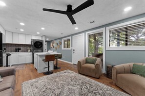 A modern kitchen with white cabinets, a black refrigerator, and a dining area with a white table and chairs. - Ozark Skyline Retreat (Branson West)