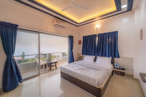 A hotel room with a bed, a nightstand, a chair, and a balcony with curtains. - 8 BHK VILLA Momentous Villa (Mahabaleshwar)