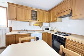 Una cucina con mobili in legno, un forno a microonde, una lavastoviglie, un fornello e una lavatrice.