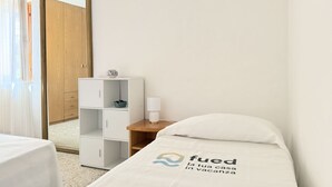 Quarto de hotel com cama, mesa de cabeceira, espelho, guarda-roupa e janela com cortinas.