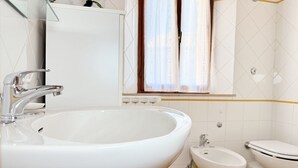 Casa de banho com lavatório branco, bidé e sanita.