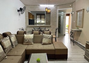 Ein Wohnzimmer mit Ecksofa, Couchtisch und einem Essbereich mit Stühlen.