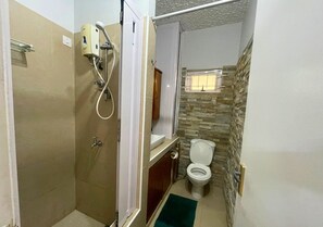 Et lille badeværelse med bruser, toilet og håndvask.
