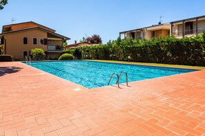 A swimming pool with a brick deck, surrounded by buildings with balconies.