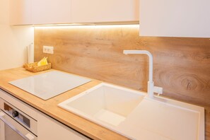 A kitchen with two white sinks, a wooden countertop, and a modern faucet.
