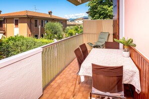 Un balcone con tavolo e sedie, una pianta in vaso e vista sugli edifici vicini.