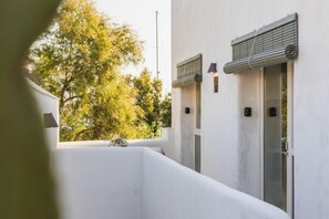 A modern building with a white exterior, a balcony with a potted plant, and a window with a view of trees. - Casa Olivera 2 bedroom apartment with 2 bathrooms, historic center of Dénia (Dénia)