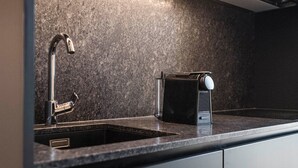 Moderni keittiö, jossa on sisäänrakennettu Bosch-mikroaaltouuni, ruostumattomasta teräksestä valmistettu hana ja tyylikäs työtaso.