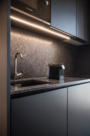 A modern kitchen with a built-in Bosch microwave, a stainless steel faucet, and a sleek countertop. - Chalet in the hay barn with private Finnish sauna (Raas)