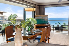 Ein Balkon mit Esstisch, Stühlen, einer Vase, einem Gemälde und Blick aufs Meer.