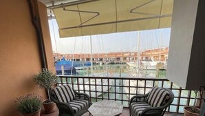 Ein Balkon mit zwei Korbstühlen, einem kleinen Tisch und Topfpflanzen.